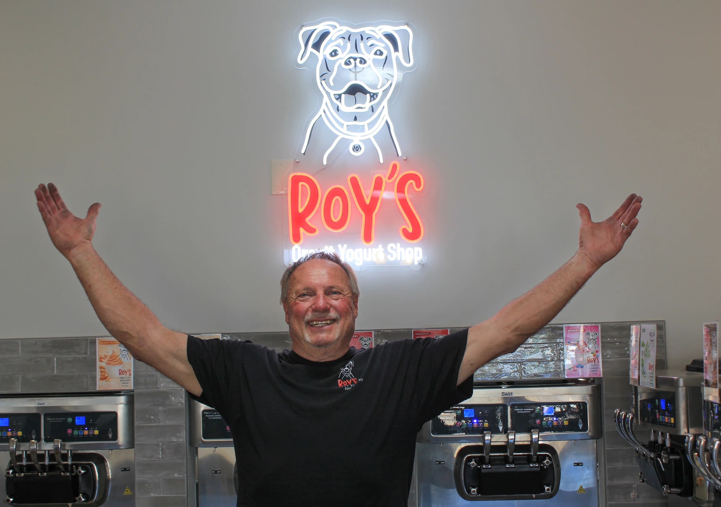 ROY’S co-owner Brian in front of the shop’s neon logo and yogurt machines